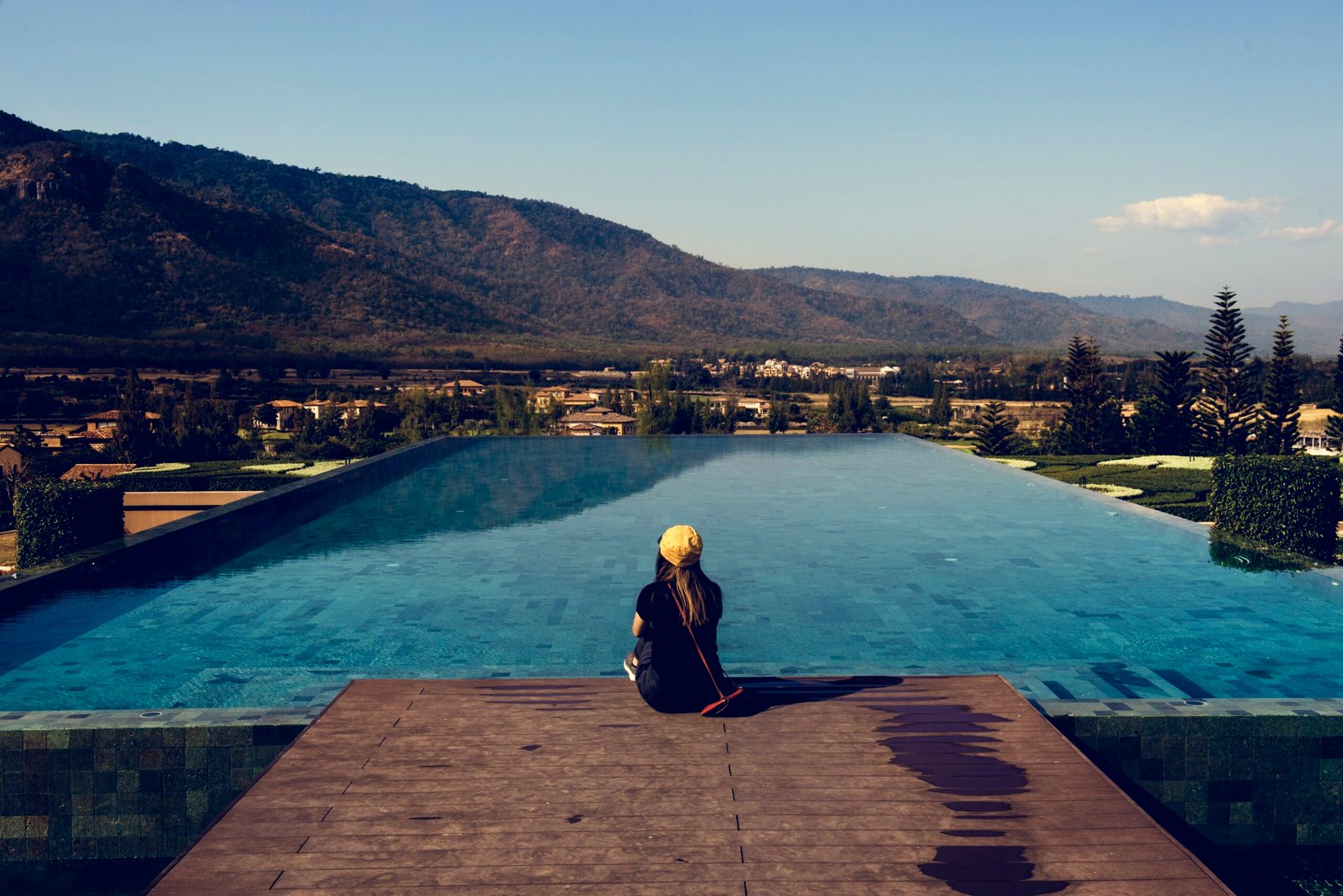 About Us Woman Sitting By Poolside Wiht Mountain View Scaled